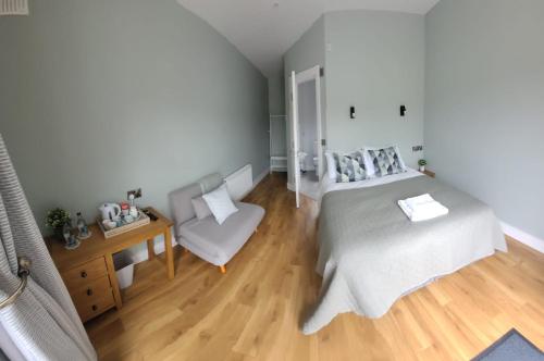 a bedroom with a bed and a chair at Stoneyford Luxurious Cabins in Stonyford