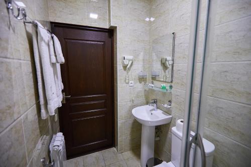 a bathroom with a sink and a toilet and a door at Elite Art Hotel in Tashkent
