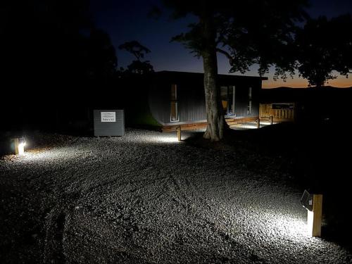 a tree and a bench in front of a house at night at Patie's Hill in Penicuik