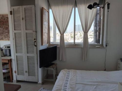 sypialnia z łóżkiem, oknem i telewizorem w obiekcie Studio avec roof top, vue d'exception, 5mn mer. w Tel Awiwie