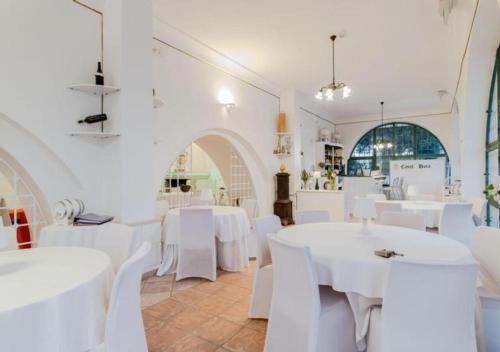um restaurante branco com mesas brancas e cadeiras brancas em Casal Duca em Taranto