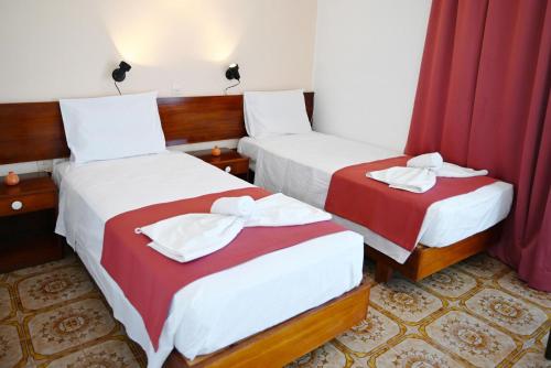 two beds in a hotel room with red curtains at Helena Apartments in Paradisi in Paradeísion