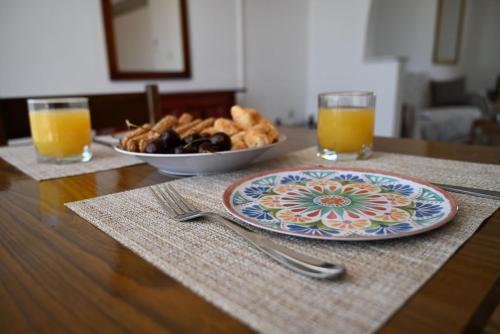 a table with a plate of food and two glasses of orange juice at Helena Apartments in Paradisi in Paradeísion