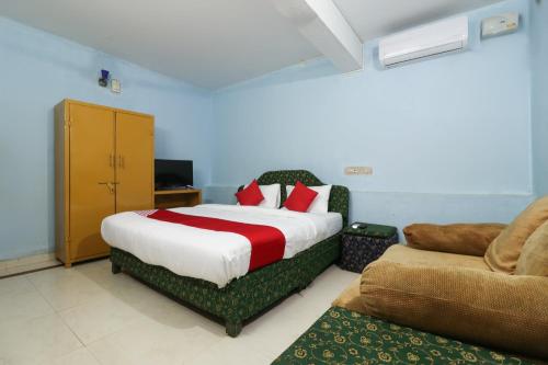 a bedroom with a bed and a chair and a couch at OYO Flagship Sandhra Apartments in Pūvār