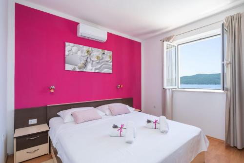 ein Schlafzimmer mit einer rosa Wand und einem großen Bett in der Unterkunft House Planika in Slano