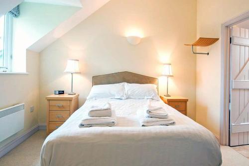 a bedroom with a white bed with towels on it at Mill Village 75, Tide Cottage - P in Somerford Keynes