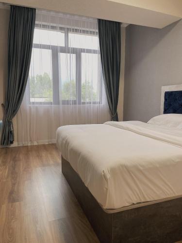 a bedroom with a large bed and a large window at Khan Plaza in Almaty