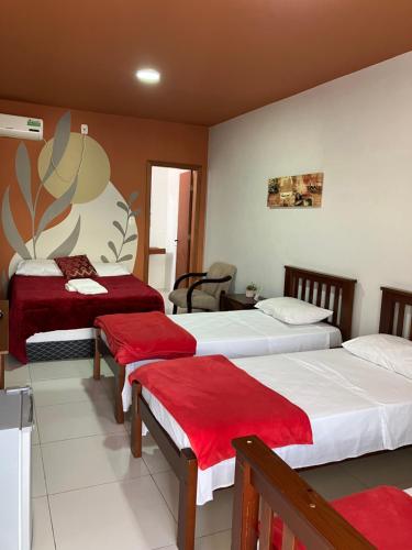 a hotel room with two beds with red sheets at Hotel Zona Sul in São Gabriel