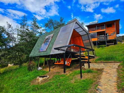 a house with a green roof on top of a hill at Glamping Hakuna Matata in Monguí