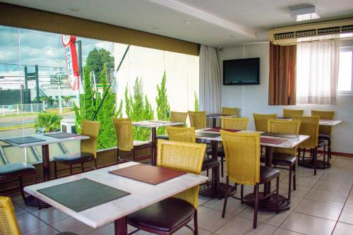 un restaurante con mesas y sillas y una gran ventana en Barigui Park Hotel, en Curitiba