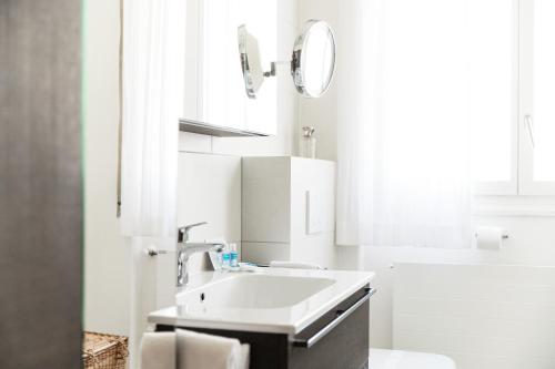 a white bathroom with a sink and a mirror at Miravalle Lakeview by Quokka 360 - large windows and magical views in Massagno