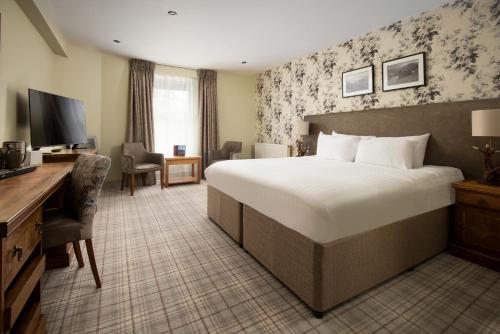 um quarto de hotel com uma cama grande e uma secretária em The Waterhead Inn- The Inn Collection Group em Ambleside