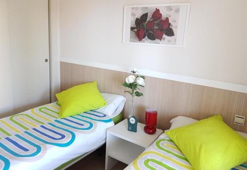 a room with two beds with yellow pillows and a table at Apartment in La Cala de Mijas in La Cala de Mijas