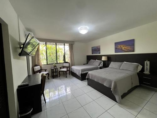 a hotel room with two beds and a table and chairs at Hotel Casa Pamplona in San Salvador