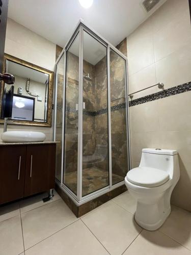 a bathroom with a shower and a toilet and a sink at Hotel Casa Pamplona in San Salvador