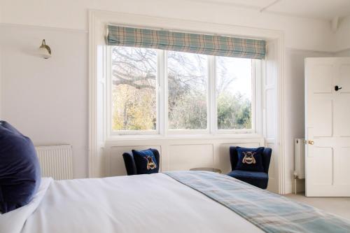 a bedroom with a bed and two chairs in front of a window at 4 Canon Lane in Chichester