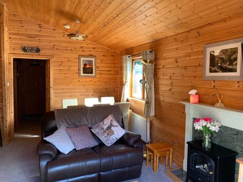 a living room with a leather couch and a fireplace at Immaculate 3-Bed Lodge in Hawick in Hawick
