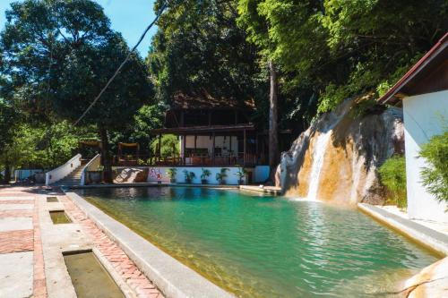 a swimming pool with a waterfall in the background at Japamala Resort by Samadhi - Adults Only in Tioman Island