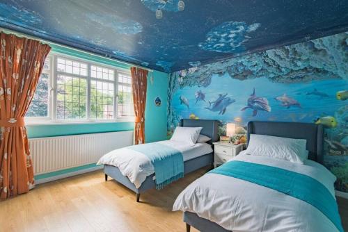a bedroom with two beds and a fish mural at Sycamores - Fabulous family home with huge garden in Kent