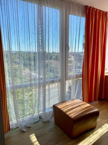 a room with large windows with a ottoman in front at Eden Apartament in Reghin