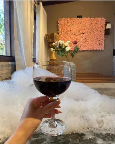 a person holding a glass of wine in a bath tub at Sanctuary Pirenópolis Suítes e Flats in Pirenópolis