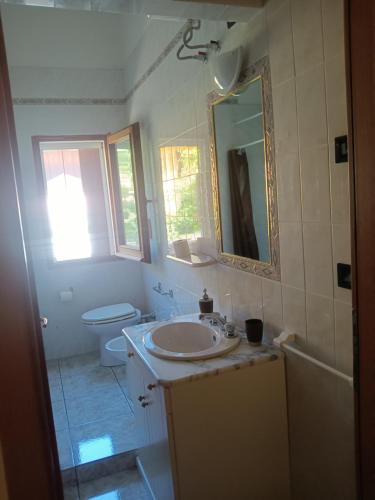 a bathroom with a sink and a toilet and a mirror at Vacanze a Solanas.....con Clima in Solanas