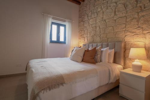 een slaapkamer met een bed met een stenen muur bij Phaedrus Living: Peristerona Traditional House in Peristerona