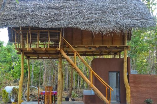 una casa en el árbol con techo de paja en Pidurangala View Treehouse, en Sigiriya