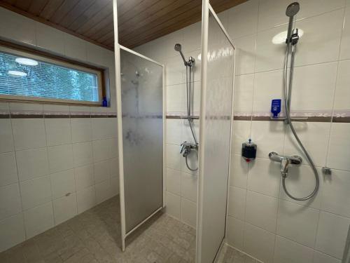 een badkamer met een douche en een glazen deur bij Porotila Toini Sanila in Sevettijärvi
