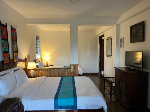 a bedroom with a large bed and a television at Maison Vu Tri Vien in Hue