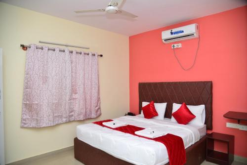 a bedroom with a bed with a red wall at Hotel V M Comfort in Bengaluru