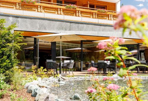 a patio with chairs and umbrellas in front of a building at Das Homann in Samnaun