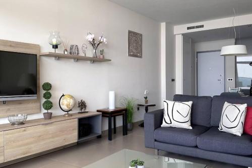 a living room with a blue couch and a tv at Luxury apartment Residencial Sunset Drive - Benidorm, España in Benidorm