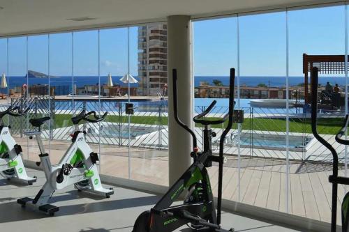 a row of exercise bikes in a gym with a view of a pool at Luxury apartment Residencial Sunset Drive - Benidorm, España in Benidorm