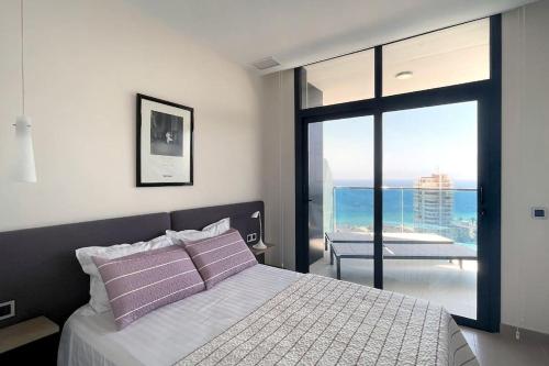 a bedroom with a bed with a view of the ocean at Luxury apartment Residencial Sunset Drive - Benidorm, España in Benidorm