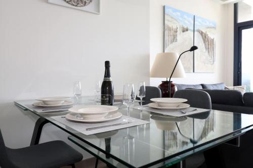 a glass dining table with glasses and a bottle of wine at Luxury apartment Residencial Sunset Drive - Benidorm, España in Benidorm