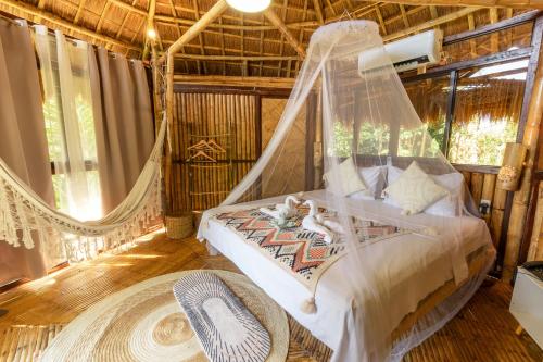 a bedroom with a bed with a hammock in it at Inigtan Lio Bamboo Cottages in El Nido