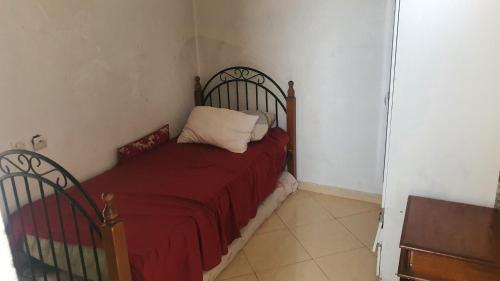 een slaapkamer met een bed met een rode deken en een kussen bij Lala safia in Fès