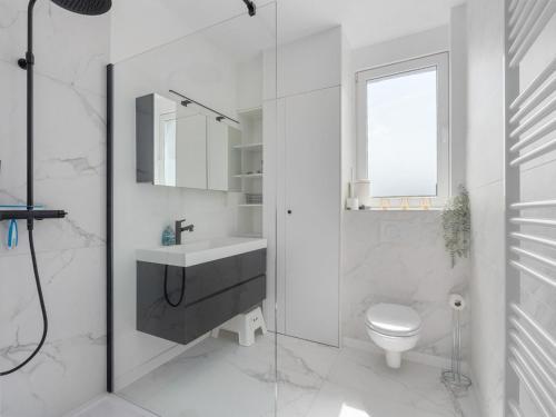uma casa de banho branca com um lavatório e um WC em A Ruzettelaan 39 3 bedrooms on floor 2 em Blankenberge