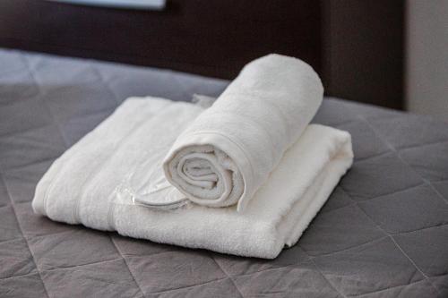 una pila de toallas blancas sentadas en una cama en Thanos Luxury home, en Volos