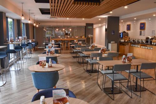 a restaurant with tables and chairs and a bar at Holiday Inn Express Leeds City Centre - Armouries, an IHG Hotel in Leeds