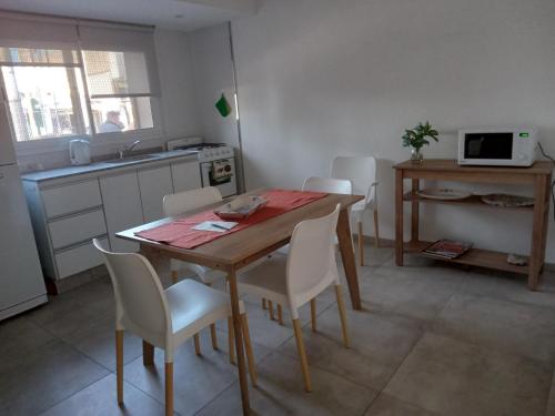 a kitchen with a wooden table and white chairs at El Puerto - Cerca de todo in Cordoba