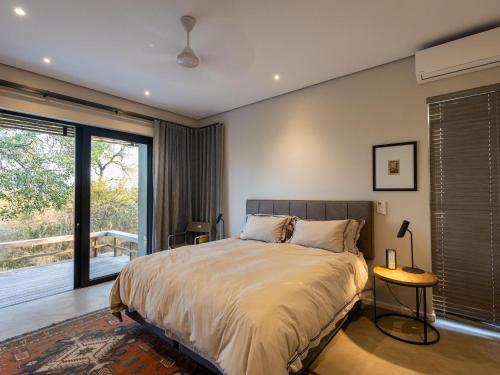 a bedroom with a bed and a large window at Lavish villa in Hoedspruit with hot tub in Hoedspruit