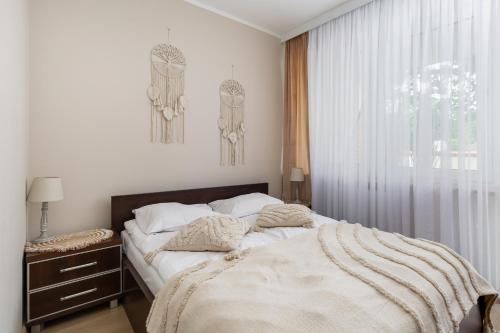 a white bedroom with a bed and a window at Apartamenty przy Promenadzie Villa Mistral II by Renters in Świnoujście