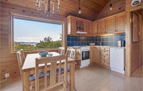 a kitchen with a table and chairs and a large window at Nice Home In Valevg With Sauna And 2 Bedrooms in Valevåg