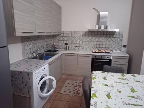 uma cozinha com uma máquina de lavar roupa e um lavatório em Casa vacanze palagianello em Palagianello