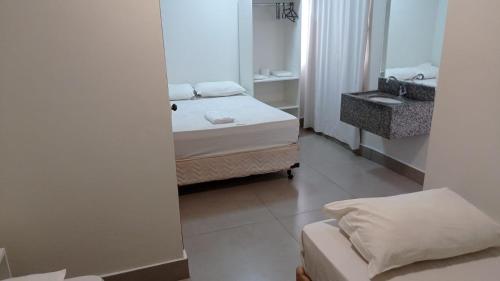 Habitación pequeña con 2 camas y espejo. en Hotel Marina Torrano en Trindade
