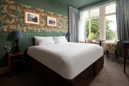 una camera da letto con un grande letto bianco e una finestra di Lakehouse at The Waterhead Inn ad Ambleside