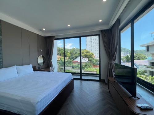 Schlafzimmer mit einem Bett, einem TV und großen Fenstern in der Unterkunft Nancy Grand Tran Group Villa 1 in Vũng Tàu