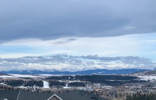 vistas a una ciudad con nieve y montañas en Cochrane’s Finest Airbnb, en Cochrane